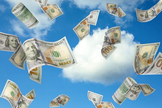 Falling American dollars and blue sky on background. Money rain