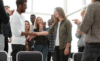 Obraz premium group of happy young people congratulating their colleague