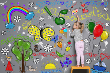 Little child drawing with colorful chalk on gray wall
