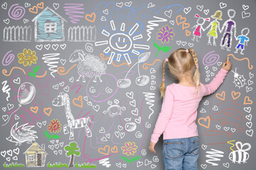 Little girl drawing with colorful chalk on gray wall