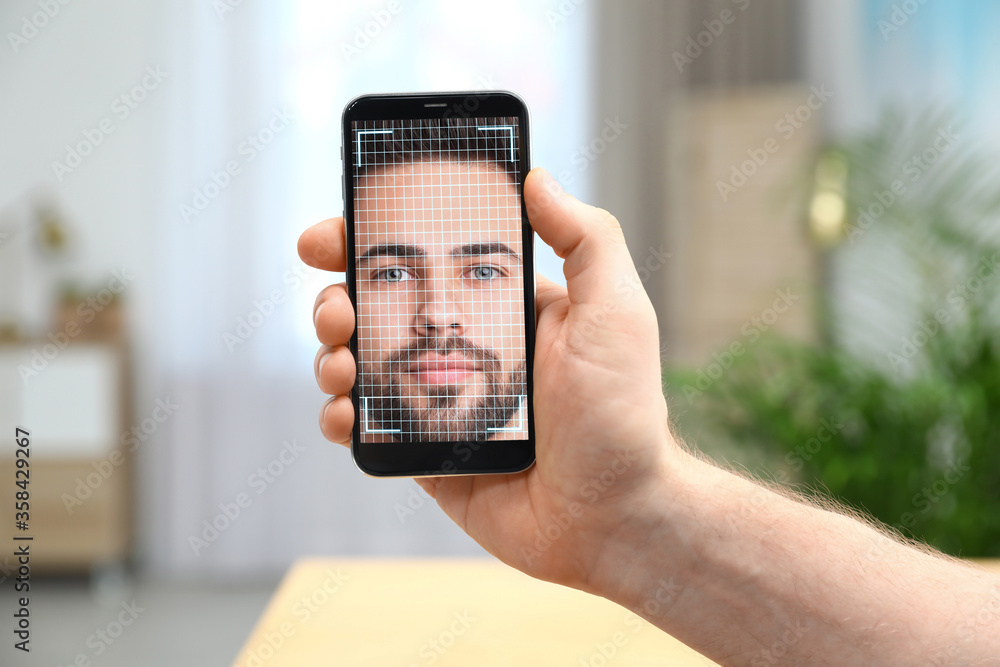 Poster man using smartphone with facial recognition system indoors, closeup. biometric verification