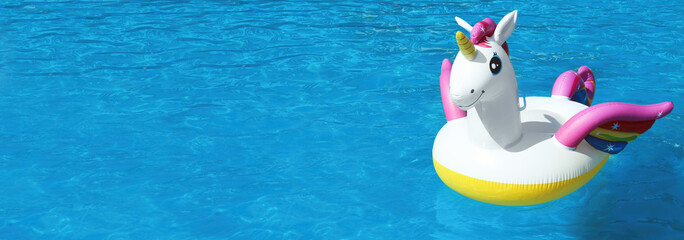 Funny inflatable unicorn ring floating in swimming pool on sunny day, space for text. Banner design