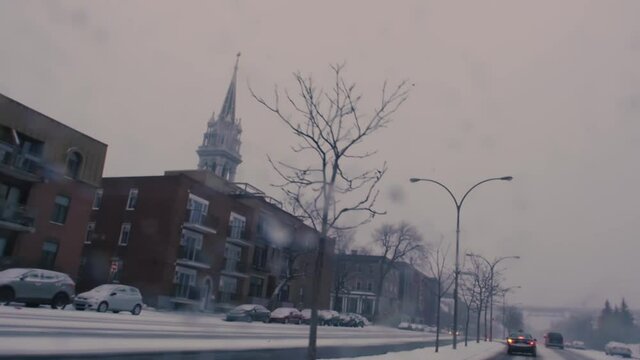 MONTREAL, CANADA - JANUARY 19 2019 Dashboard traveling camera shot of slow traffic on renee levesque street in winter. Cathedral tower in the background