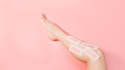 Female depilate legs with pink wax stripes against pink colored background. Removal hair....