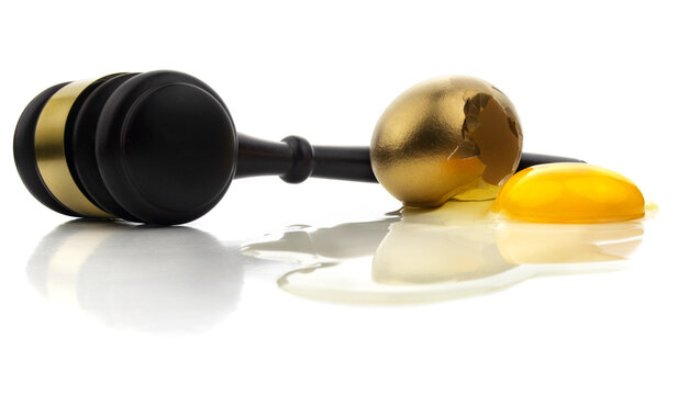 Isolated Gavel Mallet And Gold Egg Cracked With Spilled Yolk