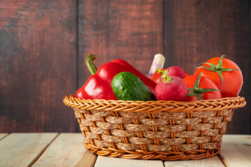 Set of fresh vegetables in a basket on a wooden background. The concept of healthy nutrition and diet.
