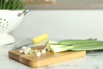 Fresh green spring onions on white marble table