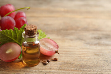 Bottle of natural grape seed oil on wooden table, space for text. Organic cosmetic
