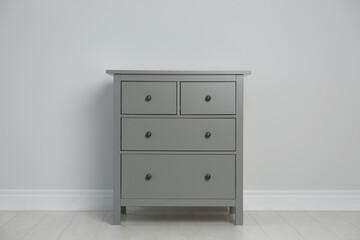 Grey chest of drawers near light wall