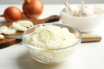 Chopped onion in bowl on white wooden table