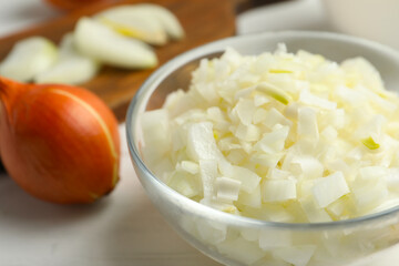 Chopped onion in bowl on white wooden table, closeup