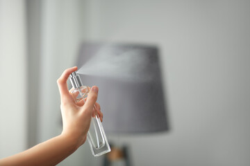 Woman spraying air freshener indoors closeup. Space for text