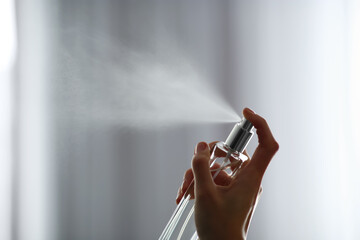 Woman spraying air freshener indoors closeup. Space for text