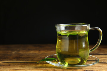 Cup of aromatic green tea on wooden table. Space for text