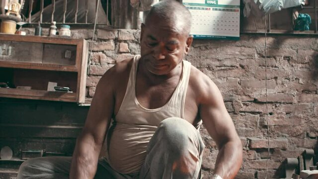 Nepali blacksmith in his workshop, hammering a metal rod on an anvil