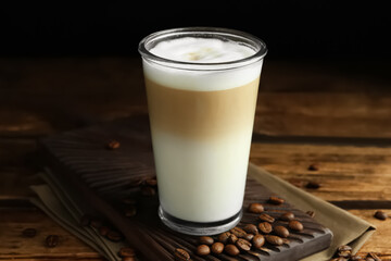 Delicious latte macchiato and coffee beans on wooden table