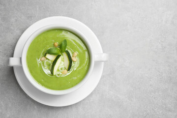 Tasty homemade zucchini cream soup on grey table, top view. Space for text