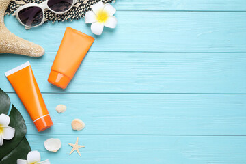 Sun protection products and beach accessories on light blue wooden background, flat lay. Space for text