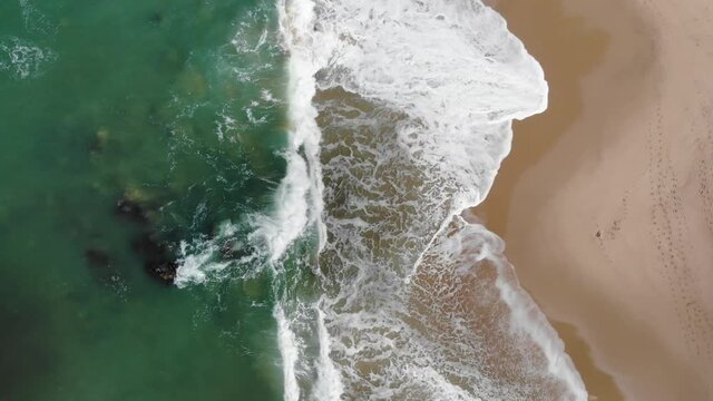 Beach on aerial drone top view with ocean waves reaching shore.