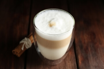 Delicious latte macchiato and cinnamon on wooden table