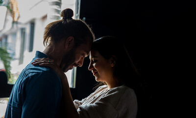 Smiling Caucasian man husband embracing his beautiful pregnant wife and looking her face with love. Couple have romantic moment together. Family bonding relationship and maternity healthcare concept.