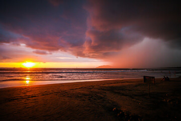 Golden sun setting against the cotton candy rainstorm sky of Tamarindo beach, Costa Rica