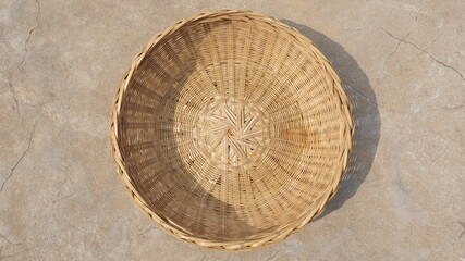 Empty round bamboo basket on the ground, top view, traditional handicraft