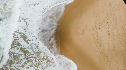 Surfing Aerial, Beach on aerial drone top view with ocean waves reaching shore, top view aerial photo from flying drone of an amazingly beautiful sea landscape.