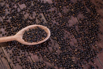 A lot of blackpeppers on wooden background.