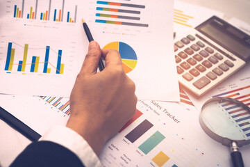 Asian accountant working and analyzing financial reports project accounting with chart graph and...