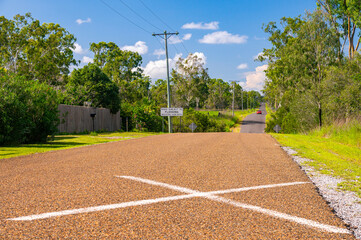 Car on asphalt country road (Schilling Road, Calliope) in queensland, with telephone poles and lines running alongside