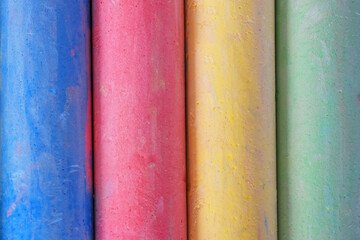 An abstract image of red, blue, yellow, and green sidewalk chalk. 