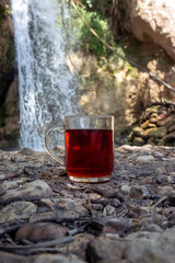 A cup of hot and delicious tea against a waterfall