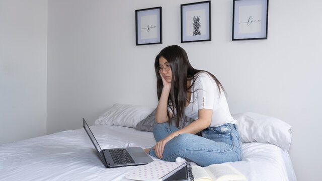 young girl with boring expression in front of the laptop.
