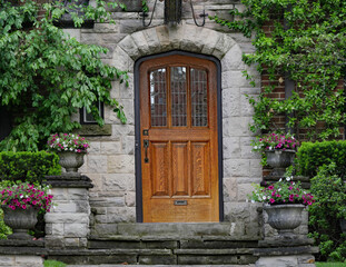 Fototapeta na wymiar elegant wooden front door wtih leaded glass, surrounded by vines and shrubs