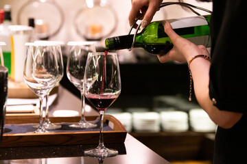 Hand pouring a red wine from bottle to a glass.