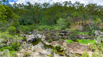 Fototapeta na wymiar Kroombit Tops National Park summer landscape with fresh water creek and swimming hole and vibrant green vegetation, Queensland
