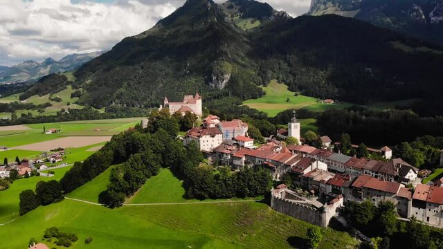 Aerial shot of the castle in Gruyeres (Switzerland). The drone is flying away and tilting down at the same time. The Castle of Gruyeres is also home to the museum of H. R. Giger.