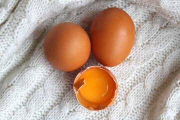 Three chicken eggs, top view, half-broken with yolk