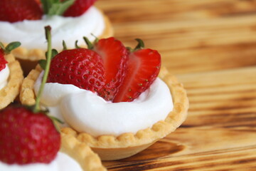 Tartlets with cream and strawberries on a wooden table