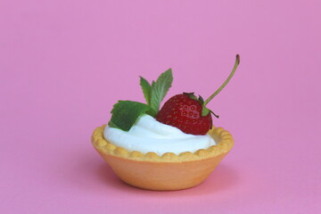Tartlet with cream and ripe strawberries on a pink background