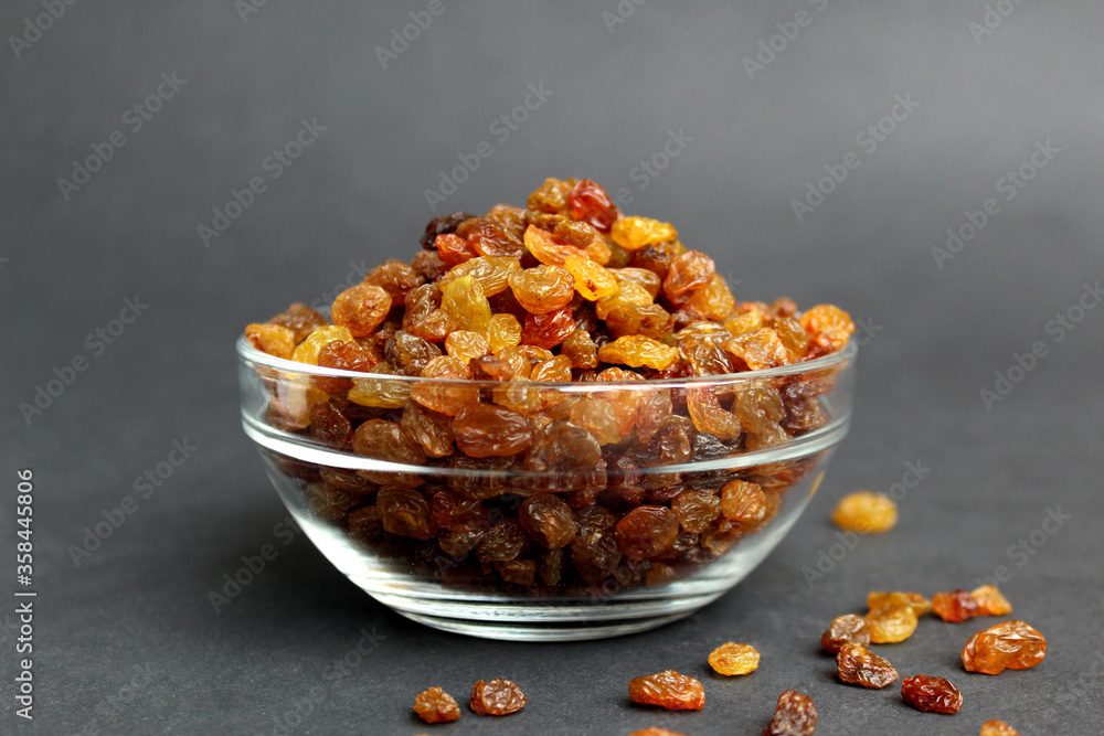 Wall mural Raisins in a glass transparent bowl on a black background