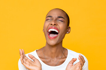 Close up portrait of happy young African American woman laughing out loud with both hands in clapping gesture isolated studio yellow background