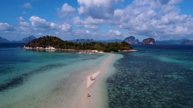 Aerial reveals three young traveller friends on isolated topical island in El Nido, Palawan