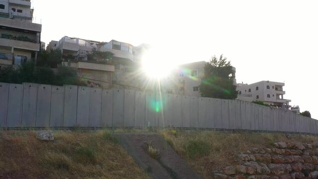 Palestine Refugges Camp Behind Concrete wall with sun flares-aerial
Dolly shot,Anata,Jerusalem,June,2020
