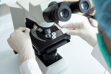 doctor placing virus sample under microscope, concept coronavirus research