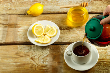 Fresh tea from the teapot is poured into a white cup.