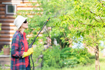 A woman sprays trees in the garden