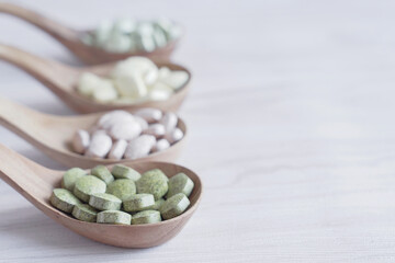 Natural cruciferous vegetables and alternative herbal tablet pills in wooden spoons, keto diet...