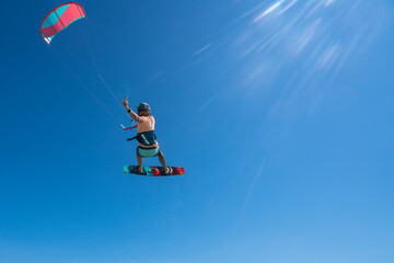 kiter does a difficult trick on a background of transparent water and blue sky